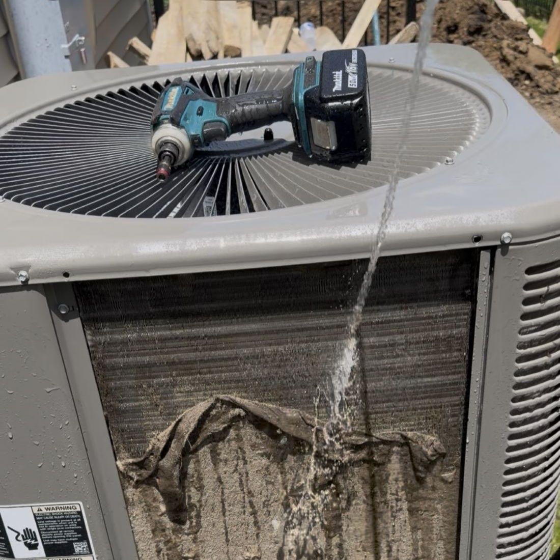Heavily clogged outdoor AC coil being washed during a Pure Comfort service call in Carpentersville, Illinois