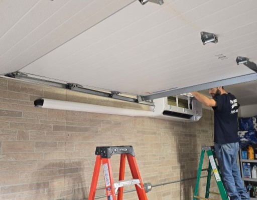 Pure Comfort technician on a ladder installing a ductless mini-split high on a garage wall