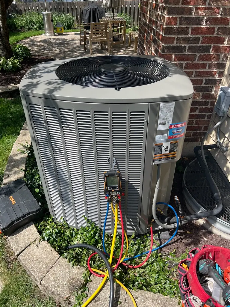 Pure Comfort technician checking refrigerant charge on a Lennox air conditioner in Elmhurst, IL