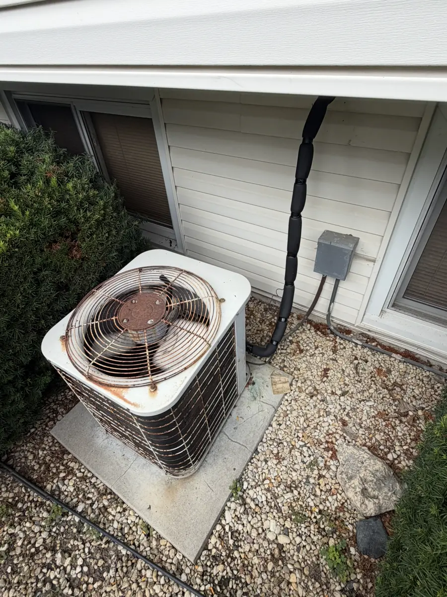 Old rusted air conditioner beside a Hanover Park, IL home before Pure Comfort replaced it