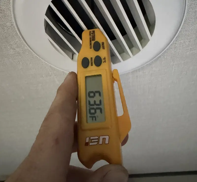 Pure Comfort technician checking AC supply air temperature at a vent in a Lombard, IL home