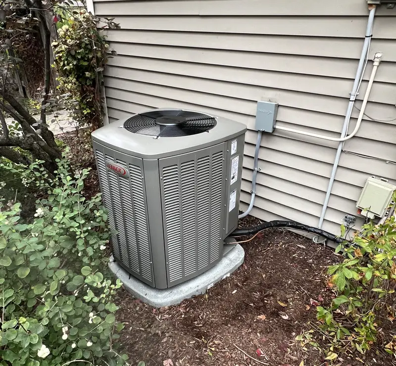 New Lennox air conditioner on a pad beside the landscaping at an Elk Grove Village, IL home