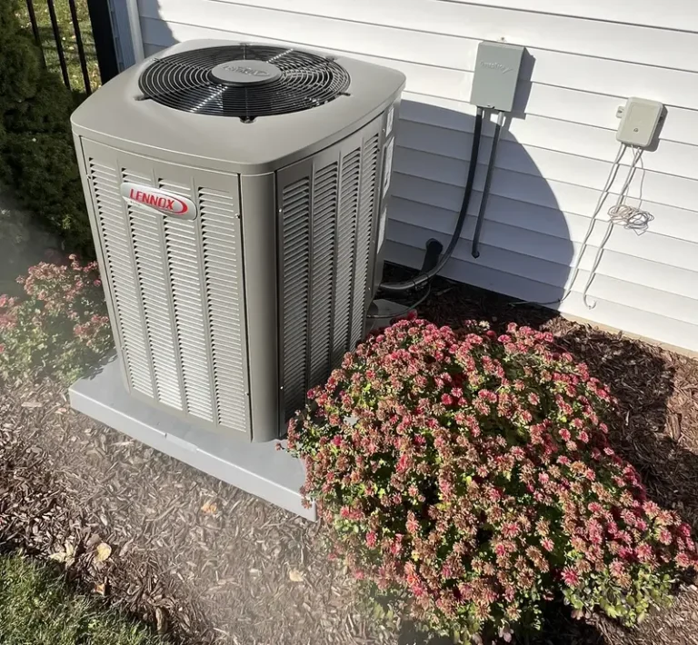 New Lennox Elite air conditioner on a pad beside the landscaping at a South Elgin, IL home