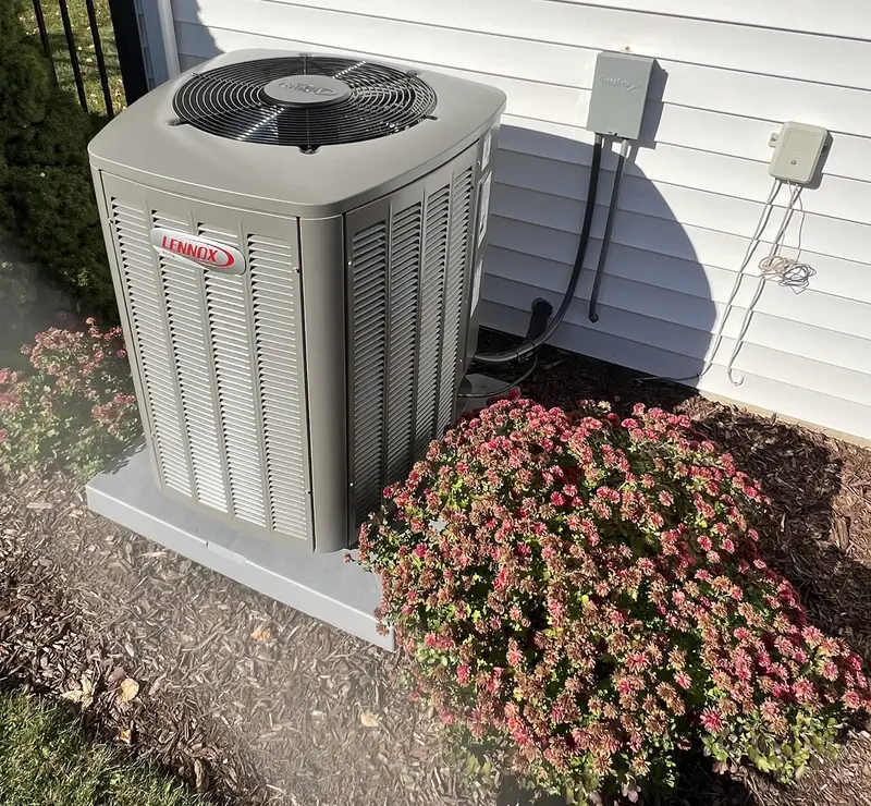 New Lennox Elite air conditioner on a pad beside the landscaping at a South Elgin, IL home